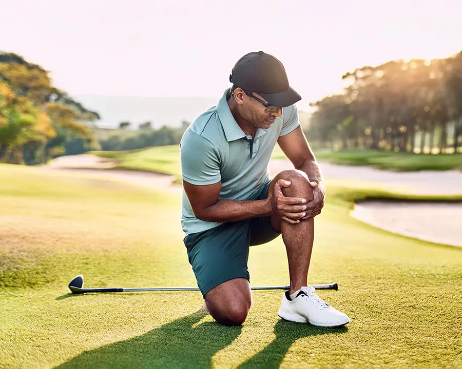 Golfer gripping knee in pain on the course, a common sign of osteoarthritis