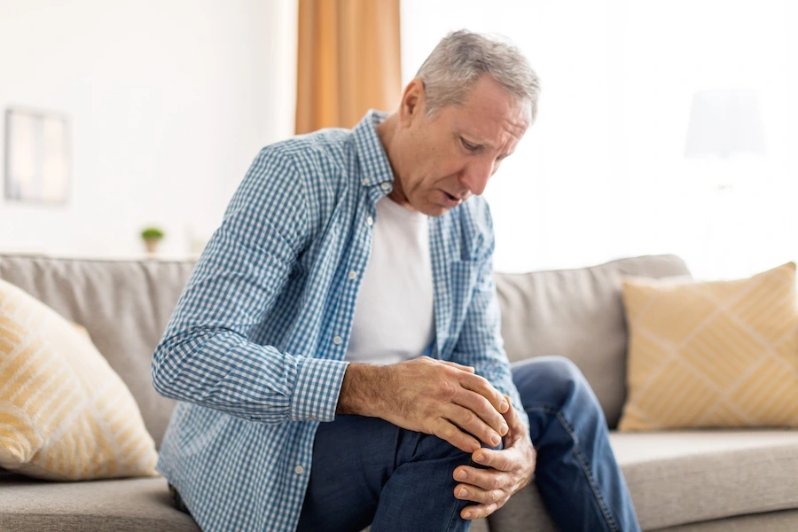 Person massaging aching leg, illustrating common vein disease symptoms
