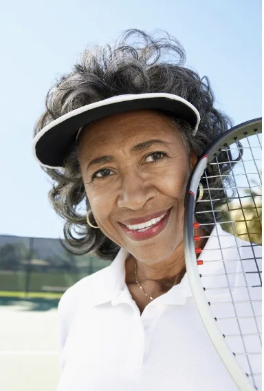 Smiling older woman on tennis court enjoying an active lifestyle after GAE knee pain relief in Atlanta