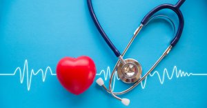 red rubber heart and stethoscope on blue background with cardiogram, health concept; blog: Can Peripheral Artery Disease Affect Heart Health?